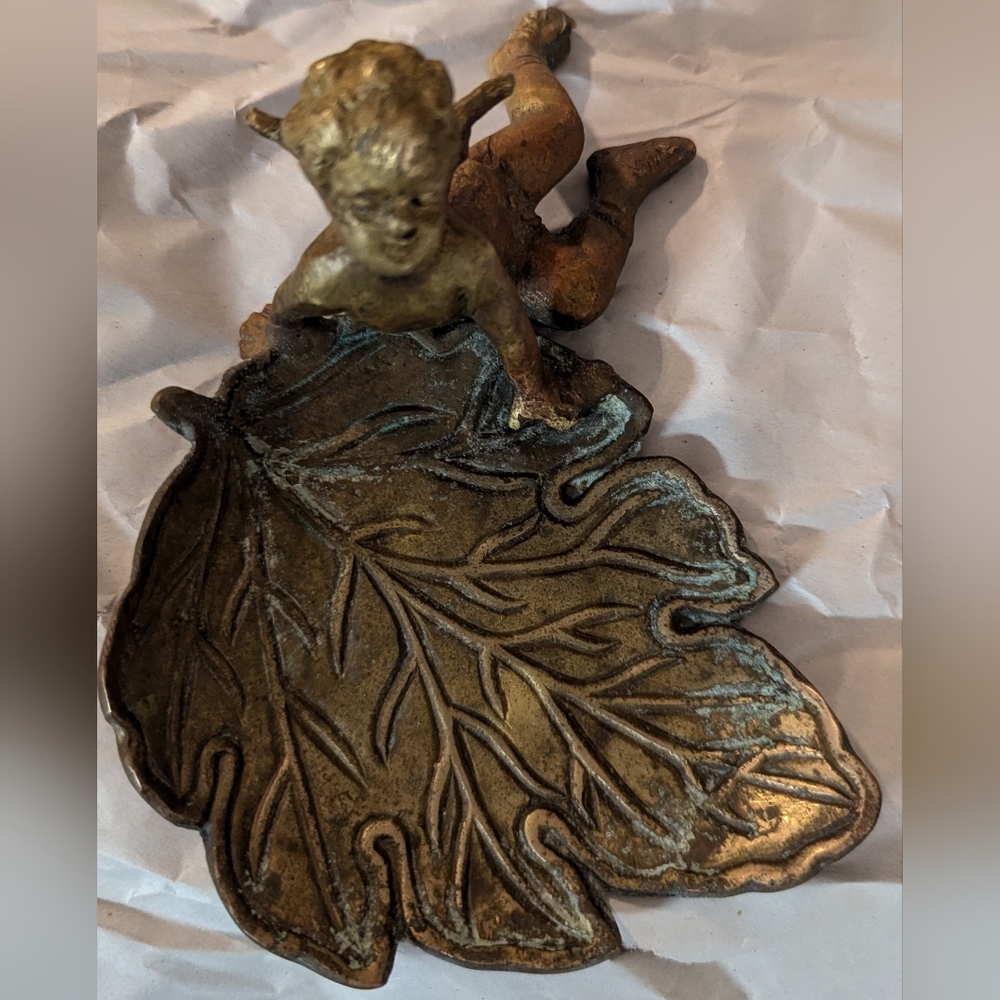 Antique bronze  trinket tray with angel sitting on side of it